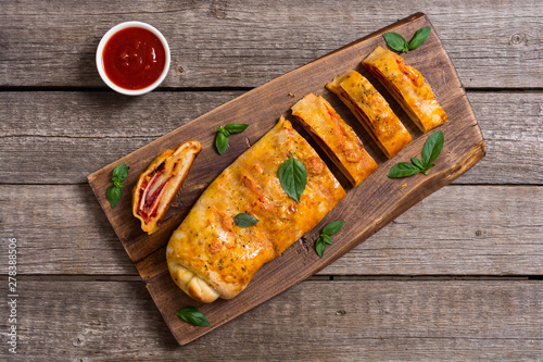 Pizza roll stromboli with cheese salami olives and tomatoes