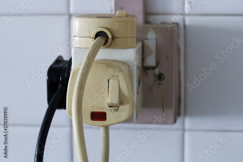 Household multi plug overloaded with old plugs. UK 3 pin plug, old with paint peeling  photo