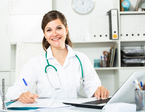 Smiling woman doctor working effectively in her office