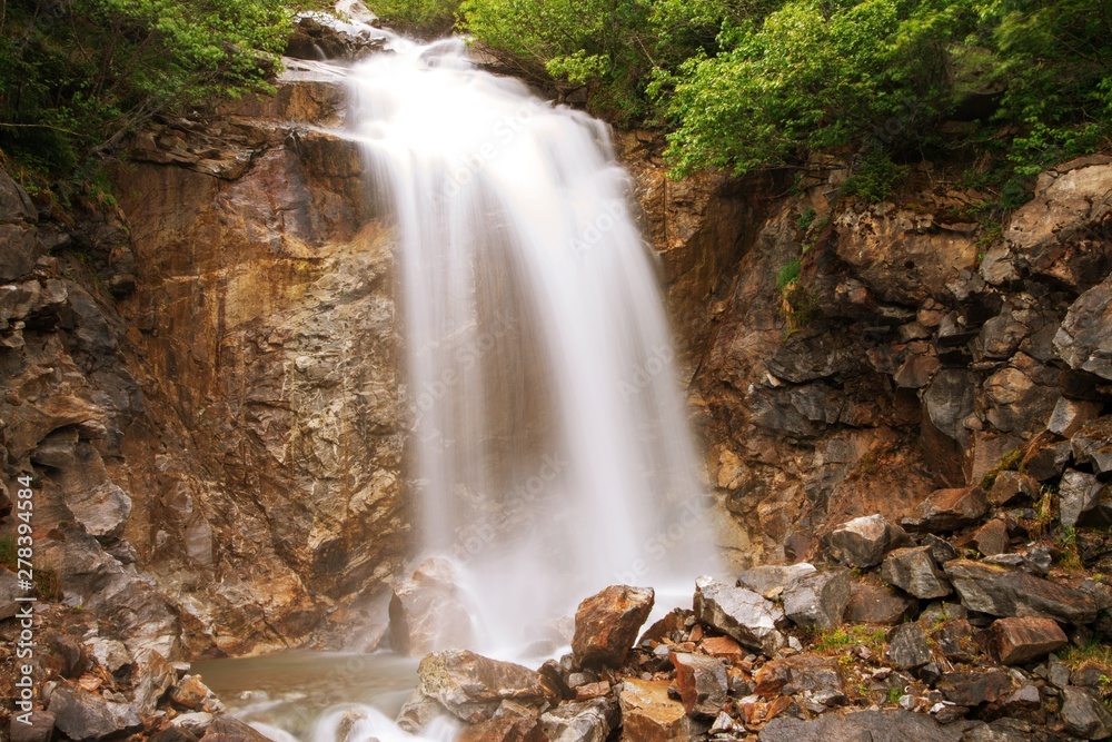 Fototapeta premium Waterfall outside of skagway alaska, with pine trees and jagged rocks
