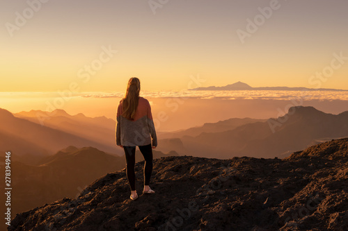 Happy young woman standing and enjoying life at sunset in mountains - gran canaria, spain