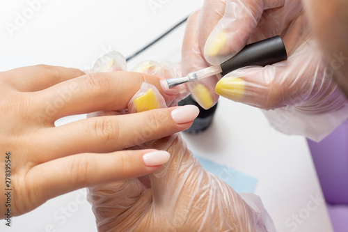 applying gel polish on the nails. shellac. manicurist makes manicure in the salon. natural color varnish. nude hue