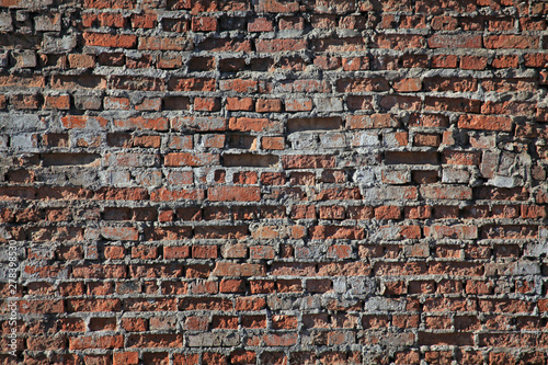 Old brick wall texture. The wall, made of old red bricks, darkened by old age. Ancient vintage brick wall background. Brick wall backdrop photo