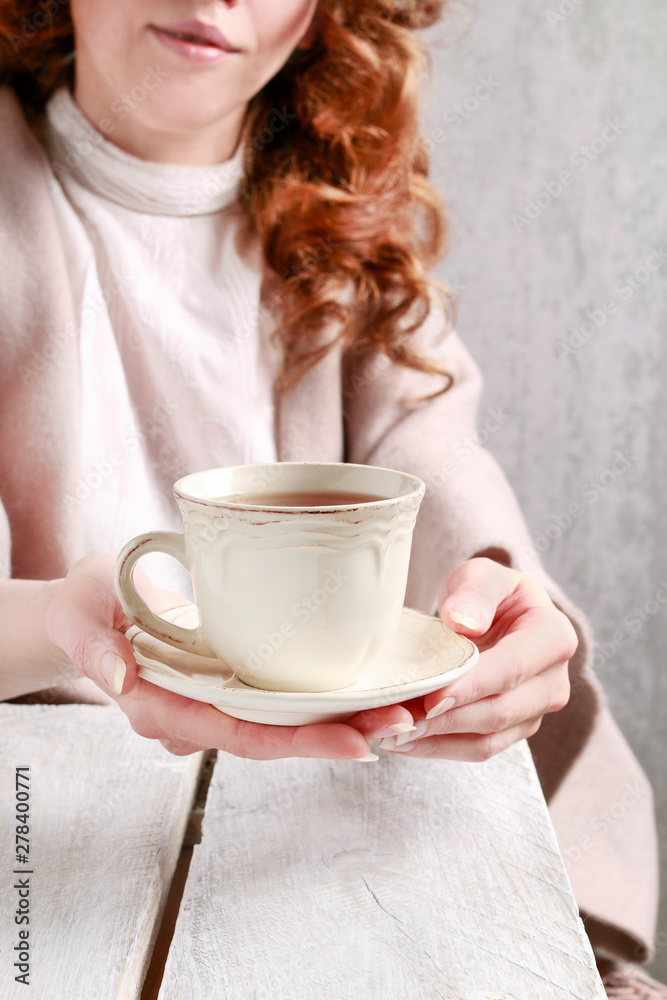 A woman is giving a cup of tea.
