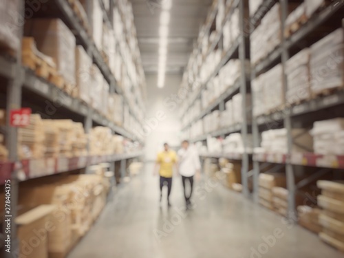 Blurred image of People or beautiful business woman customer shopping with flatbed cart at furniture and buy home accessories for house in warehouse or distribution storehouse with Shelf.