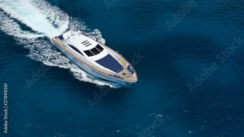 Aerial drone tracking photo of luxury yacht with wooden deck cruising in deep blue waters of Mykonos island, Cyclades, Greece © aerial-drone