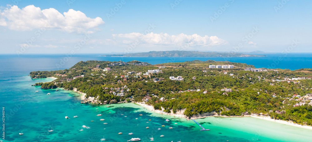 Tourist boats off the coast of the island of Boracay, Philippines, aerial view. Big island with hotels and a white beach. Seascape with a beautiful coast.