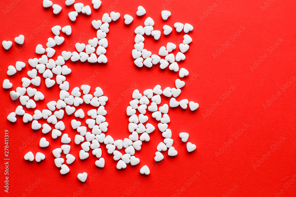 White pills in the shape of a heart on a red background. Red cross symbol. Copy space