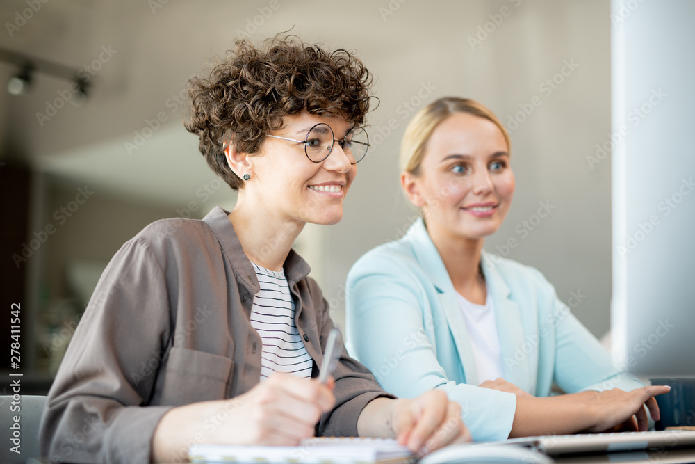Fototapeta premium Two happy female colleagues looking at data on computer screen