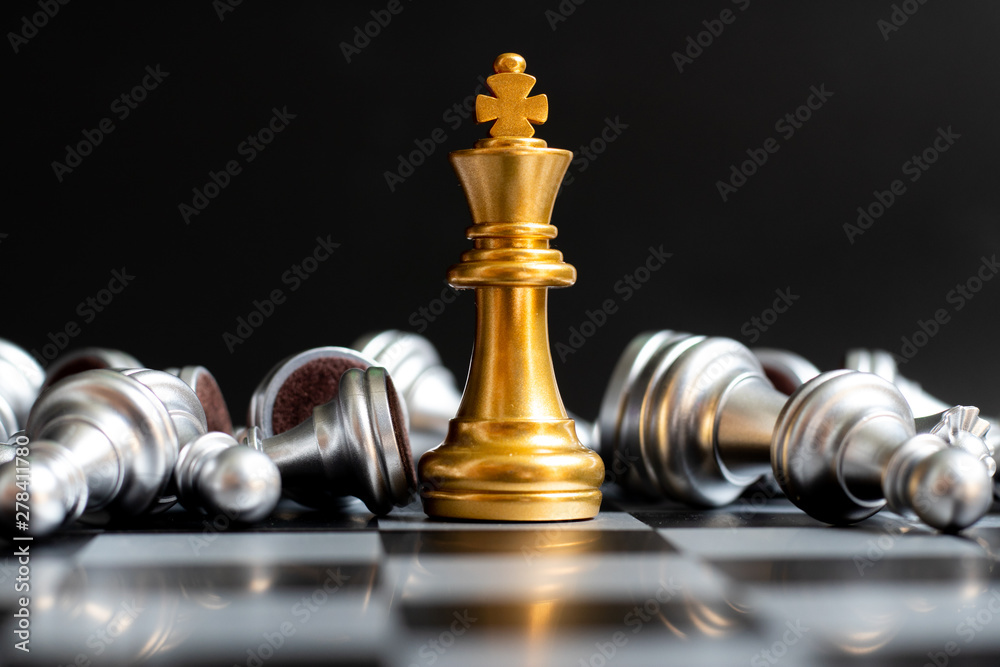 Gold king chess piece win over lying down silver pawn on black