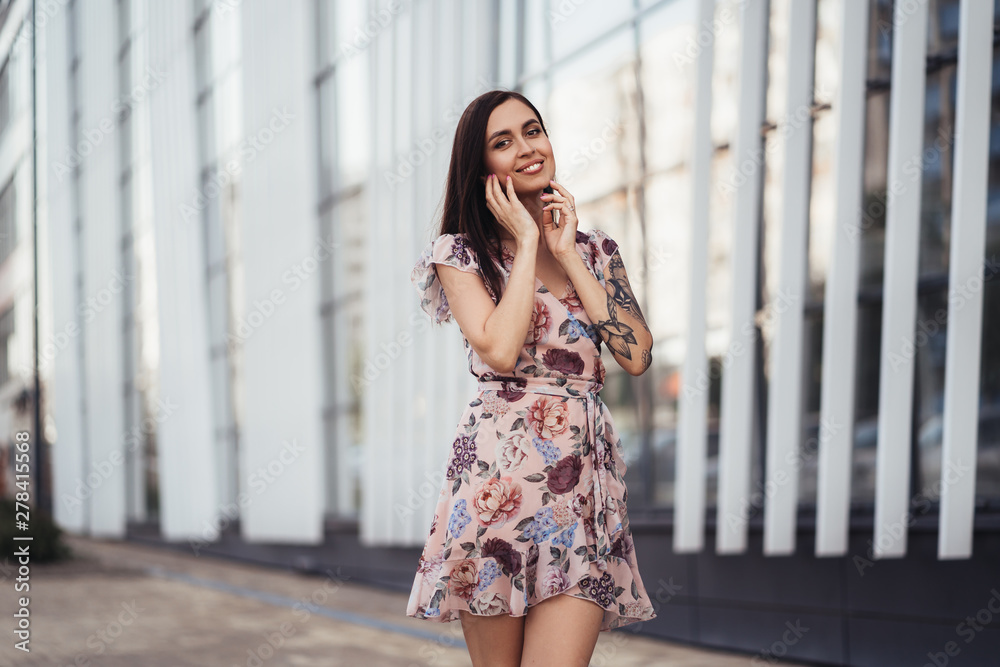 Attractive brunette girl in colored dress posing near modern building. Attractive brunette girl in colored dress posing near modern building.