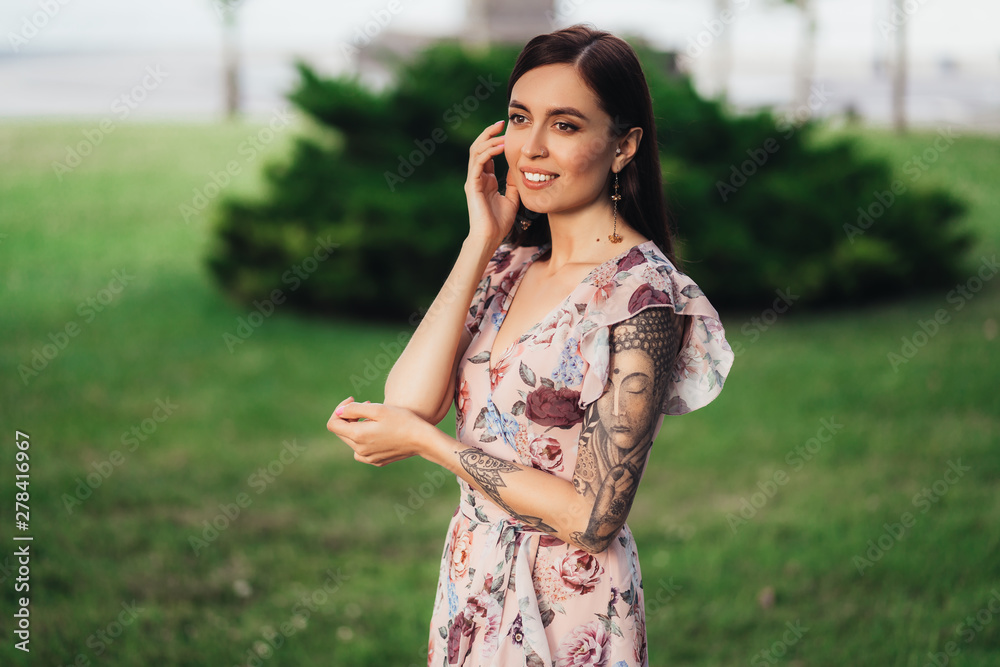 Smiling girl in dress with tattoo on her hands posing of greenery on background Smiling girl in dress with tattoo on her hands posing of greenery on background