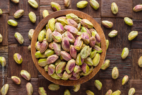 pistachios nuts peeled in wooden bowl, top view. photo
