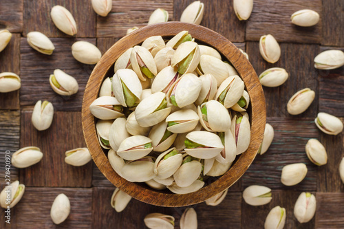 shelled pistachio nuts in wooden bowl, top view. photo