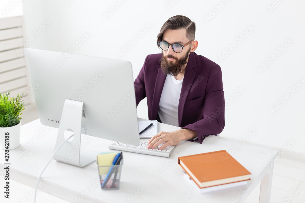 People and technology concept - Attractive man with beard working on at the computer People and technology concept - Attractive man with beard working on at the computer