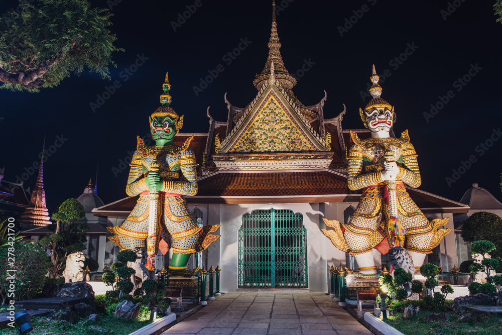 Wat Arun Temple of Dawn Buddhist temple with guardians protecting gates. Bangkok, Thailand.