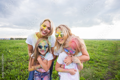Family, festival of holi and holidays concept - portrait of mothers and daughters covered in paint