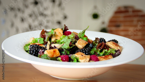 Healthy salad bowl with grilled chicken, caramelized onion and berries.