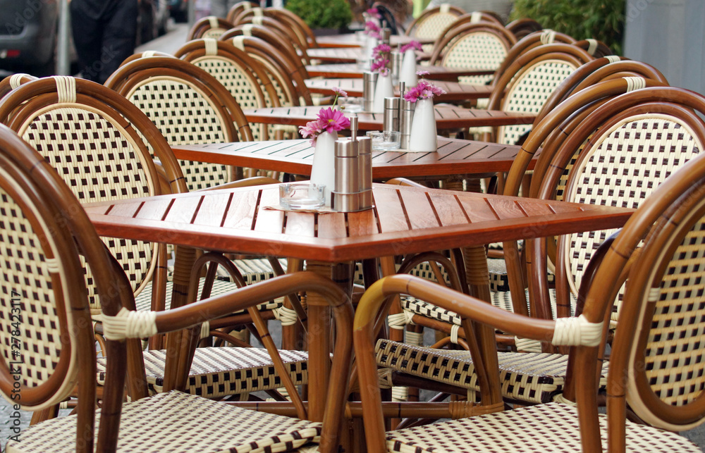 Tables and chairs on empty terrace of a street cafe