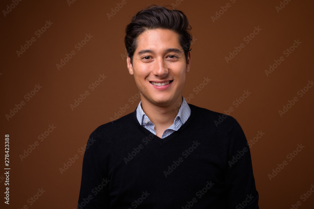Fototapeta premium Young multi-ethnic handsome man against brown background