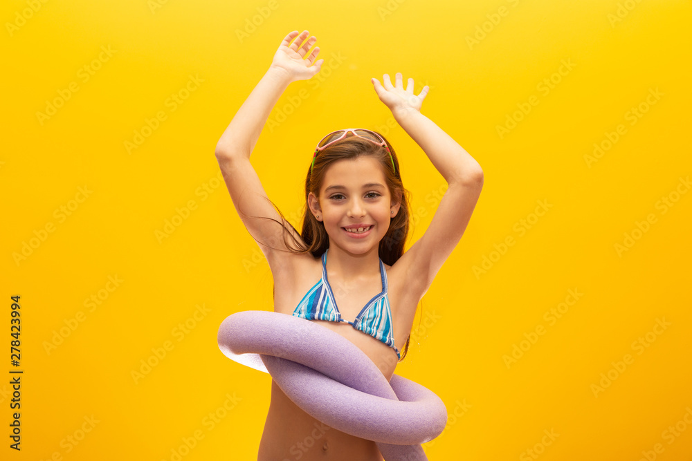 Child wearing bikini on yellow background. Concept of summer, beach and pool. Child wearing bikini on yellow background. Concept of summer, beach and pool.