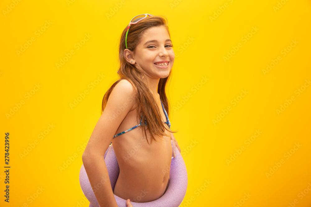Child wearing bikini on yellow background. Concept of summer, beach and pool. - obrazy, fototapety, plakaty 