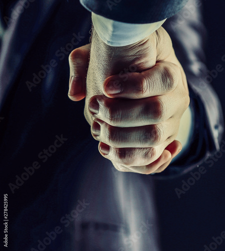 Handshake - Hand on a dark background with tinted in warm tones © yurolaitsalbert