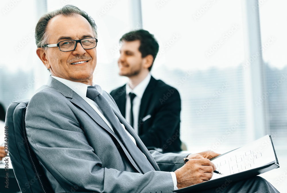 Portrait of a successful businessman in the office on the backgr Portrait of a successful businessman in the office on the backgr