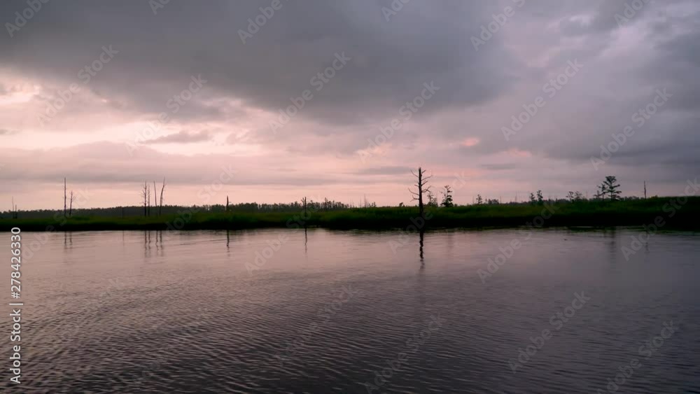 Sailing along a river as the sun sets on a cloudy day Sailing along a river as the sun sets on a cloudy day