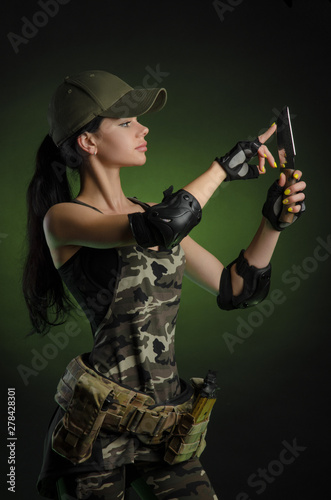 Canvas Print the girl in military special clothes posing with a gun in his hands on a dark ba
