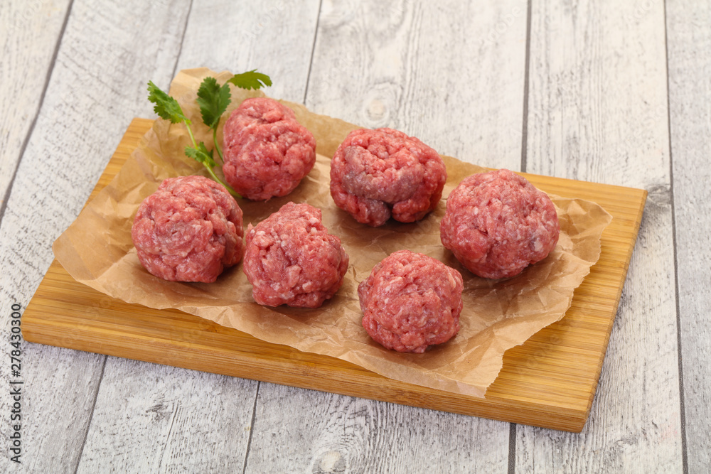 Raw meatball over wooden background Raw meatball over wooden background