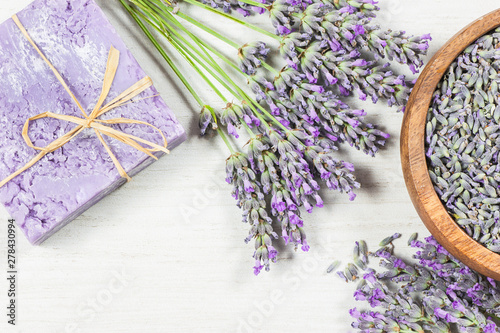 Lavender natural soap with fresh lavender flowers and dried lavender seeds on white rustic table, aromatherapy spa massage concept