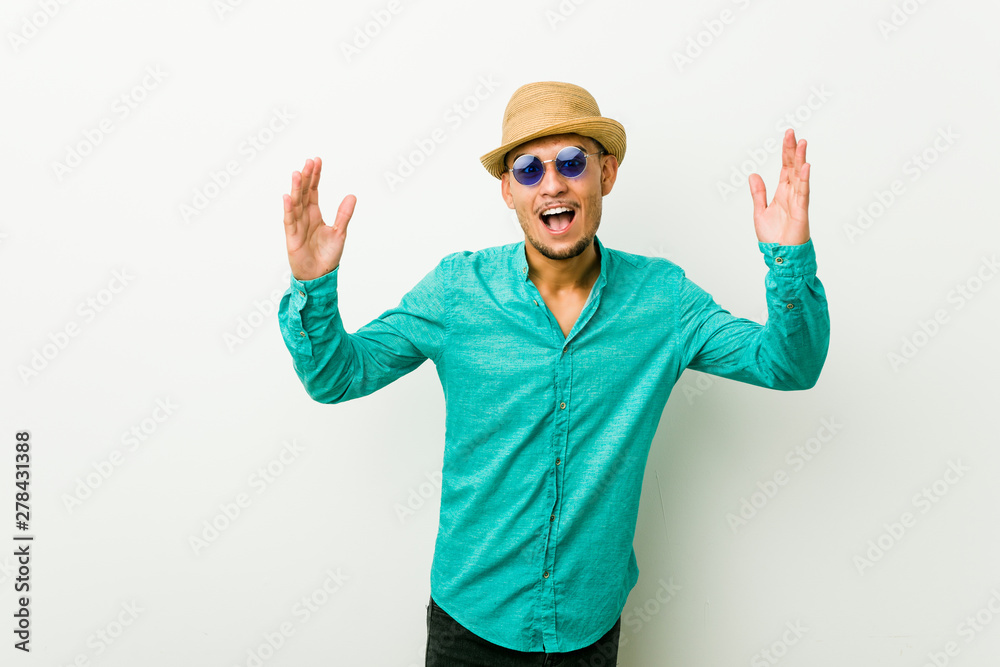 Young hispanic man wearing a summer clothes receiving a pleasant surprise, excited and raising hands. Young hispanic man wearing a summer clothes receiving a pleasant surprise, excited and raising hands.