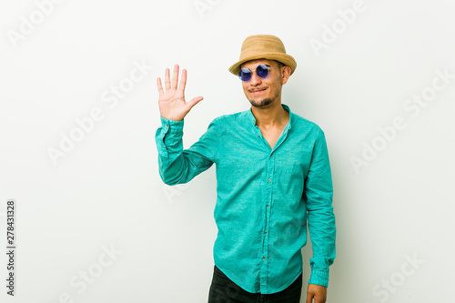 Young hispanic man wearing a summer clothes smiling cheerful showing number five with fingers. © Asier