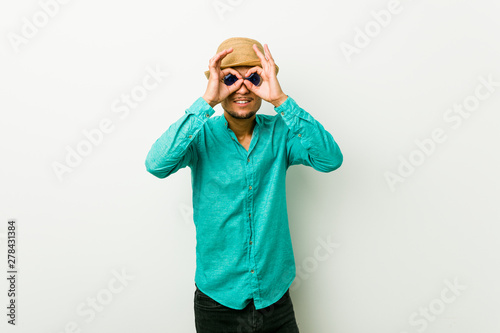 Young hispanic man wearing a summer clothes showing okay sign over eyes
