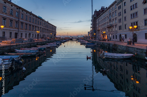 Views of the Grand Canal of Trieste at dusk creating reflections on the waters and anarajando the sky, Trieste, Italy photo