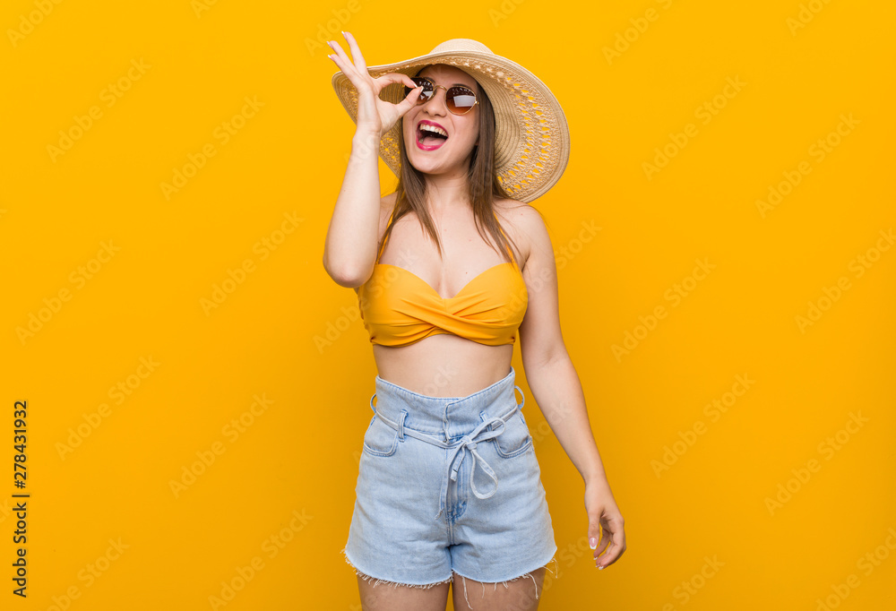 Young caucasian woman wearing a straw hat, summer look excited keeping ok gesture on eye. Young caucasian woman wearing a straw hat, summer look excited keeping ok gesture on eye.