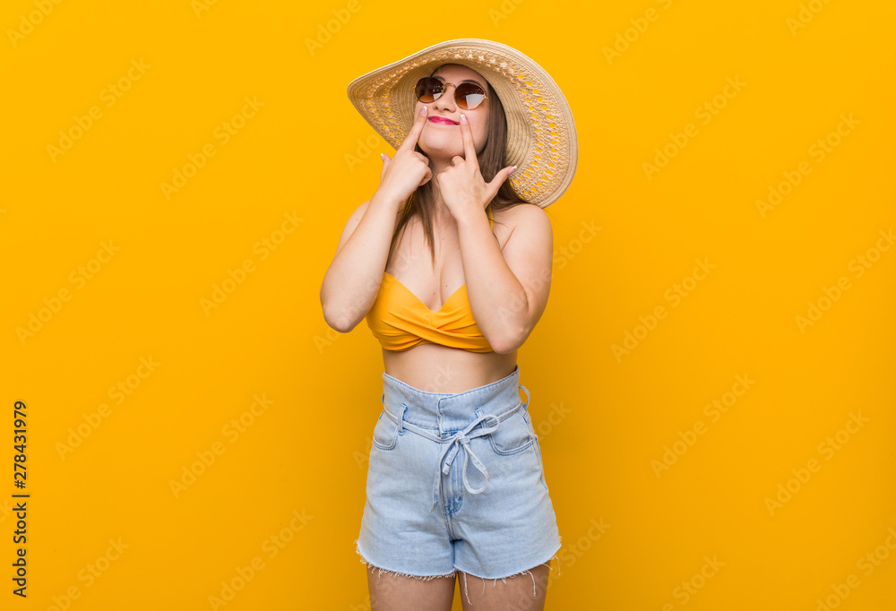 Young caucasian woman wearing a straw hat, summer look doubting between two options. Young caucasian woman wearing a straw hat, summer look doubting between two options.