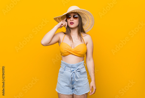 Young caucasian woman wearing a straw hat, summer look showing a disappointment gesture with forefinger.