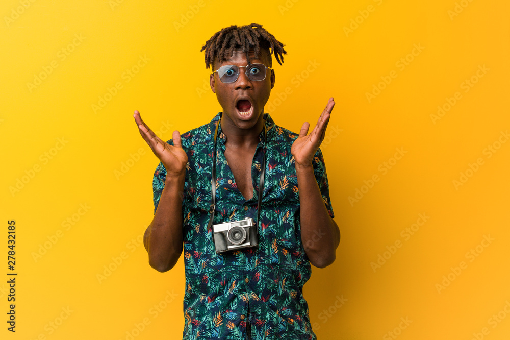 Young black rasta man wearing a vacation look surprised and shocked. Young black rasta man wearing a vacation look surprised and shocked.