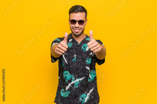 Young filipino man wearing summer clothes with thumbs ups, cheers about something, support and respect concept.