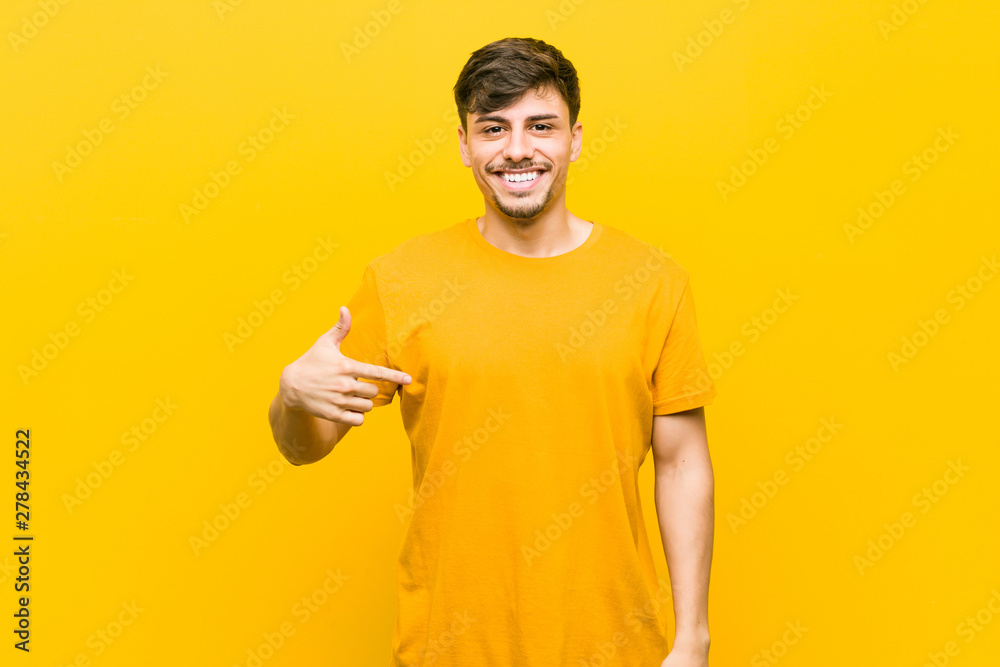 Young hispanic casual man person pointing by hand to a shirt copy space, proud and confident Young hispanic casual man person pointing by hand to a shirt copy space, proud and confident