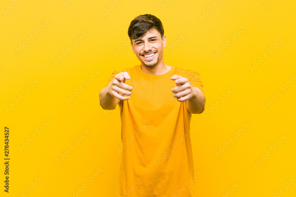 Young hispanic casual man cheerful smiles pointing to front.