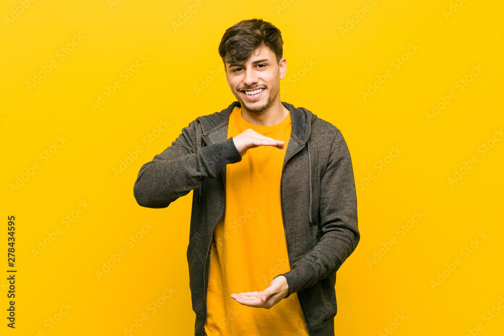 Young hispanic casual man holding something with both hands, product presentation. Young hispanic casual man holding something with both hands, product presentation.