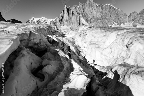 Alpinists crossing glacier crevasse, Aiguilles du Diable peak, Mont Blanc. .