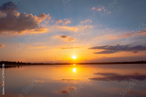 Sunset reflection lagoon. beautiful sunset behind the clouds and blue sky above the over lagoon landscape background. dramatic sky with cloud at sunset © Achira22