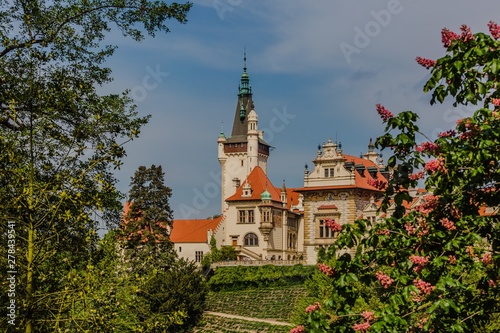 Spring view of romantic Pruhonice castle  Czech Republic  Europe  standing on hill in a park  sunny spring day with blue sky. Blooming chestnut tree in foreground. Leaves framing picture.