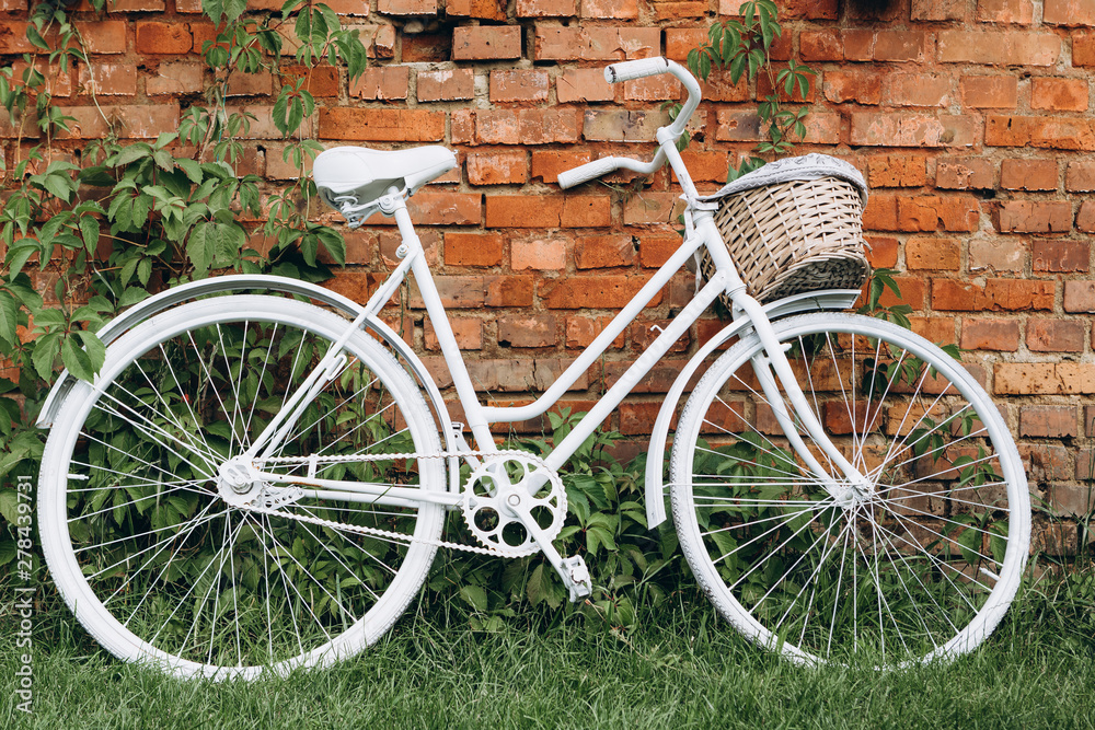 City bicycle fixed gear and red brick wall, white vintage bike. Retro stylish cycling in town, old retro bike, cycling or commuting in city urban environment, ecological transportation concept