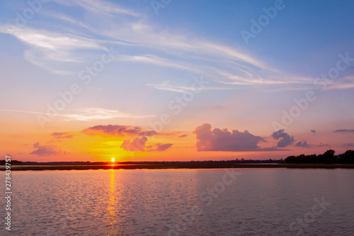 Sunset reflection lagoon. beautiful sunset behind the clouds and blue sky above the over lagoon landscape background. dramatic sky with cloud at sunset