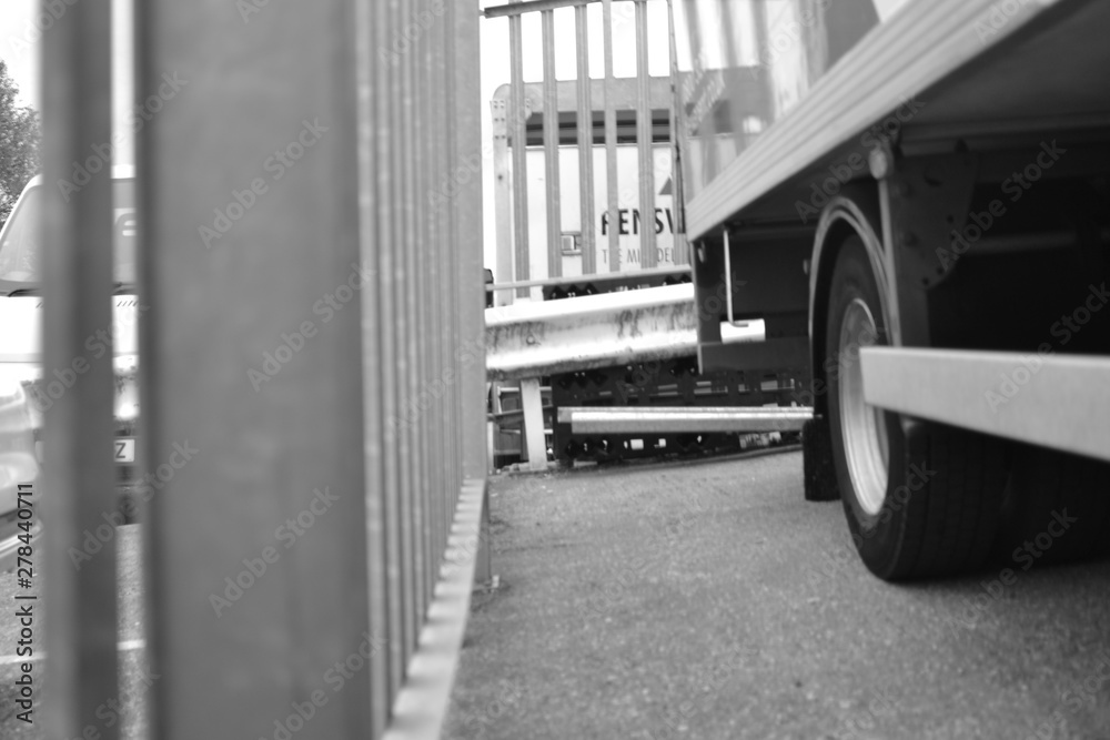 Truck parked in yard with grey railing on road